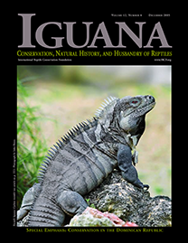 Black Page with gray text reading Iguana. Color Photo depicts a Ricord’s Iguana on a rock. He is an army green color with charcoal gray stripes and a dark red eye.